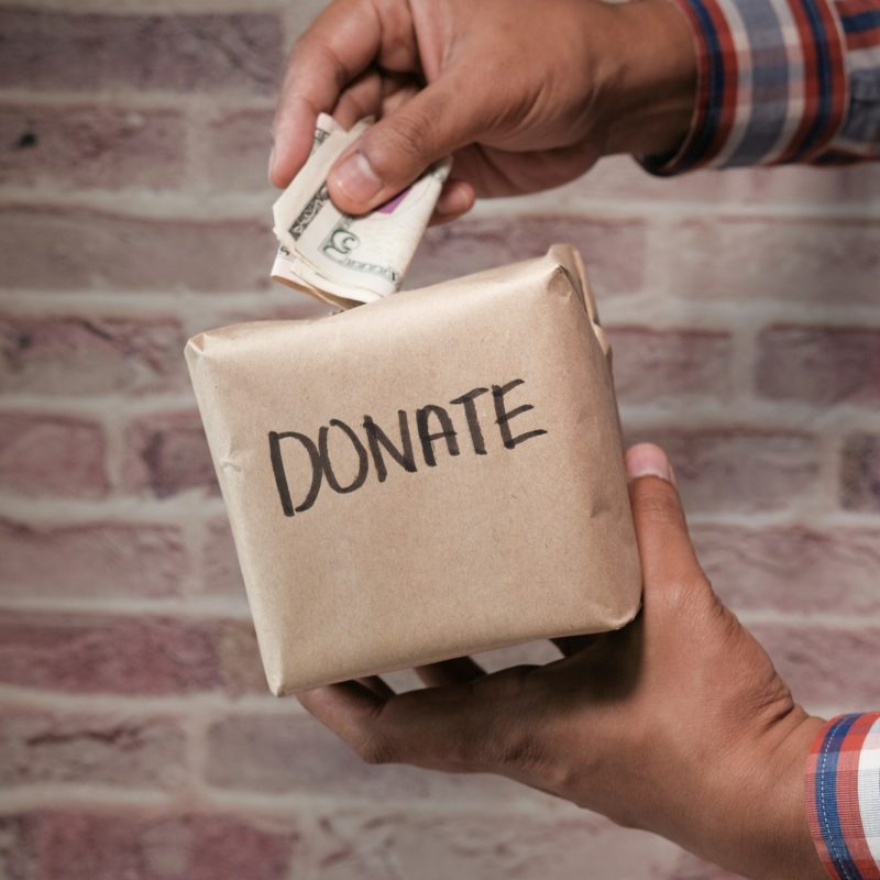 Donation box with hands inserting money symbolizes charity and support for community assistance